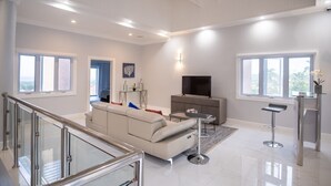 A modern living room with a sofa, TV, and a glass coffee table.