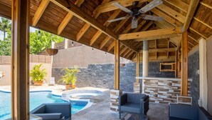 Une terrasse extérieure avec une piscine, des sièges et un mur en pierre.