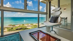 Une chambre moderne dotée de grandes fenêtres offrant une vue sur l’océan et la plage.