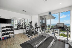 Un gimnasio moderno con cintas de correr, elípticas y un soporte para pesas.