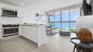 A modern kitchen with a central island, large windows with a view of the ocean, and a dining area with a view. - Peace and Light, Ocean View Condo on the 5th floor (Eagle Beach)