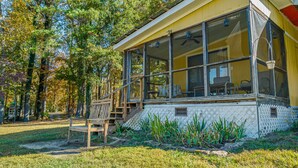 A wooden deck with a chair, a covered porch with large windows, and a view of trees. - Mountain Meadow (Mentone)