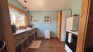 A kitchen with wooden cabinets, a refrigerator, and a microwave. - Bunkhouse with Horse Accommodations (Big Timber)