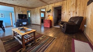 A wooden-floored living room with a television, a leather recliner, and a fireplace. - Bunkhouse with Horse Accommodations (Big Timber)