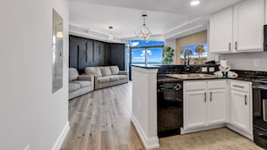 A modern kitchen with white cabinets, a black countertop, and a built-in dishwasher. - Beachfront Anderson Condos by Hosteeva (Myrtle Beach)