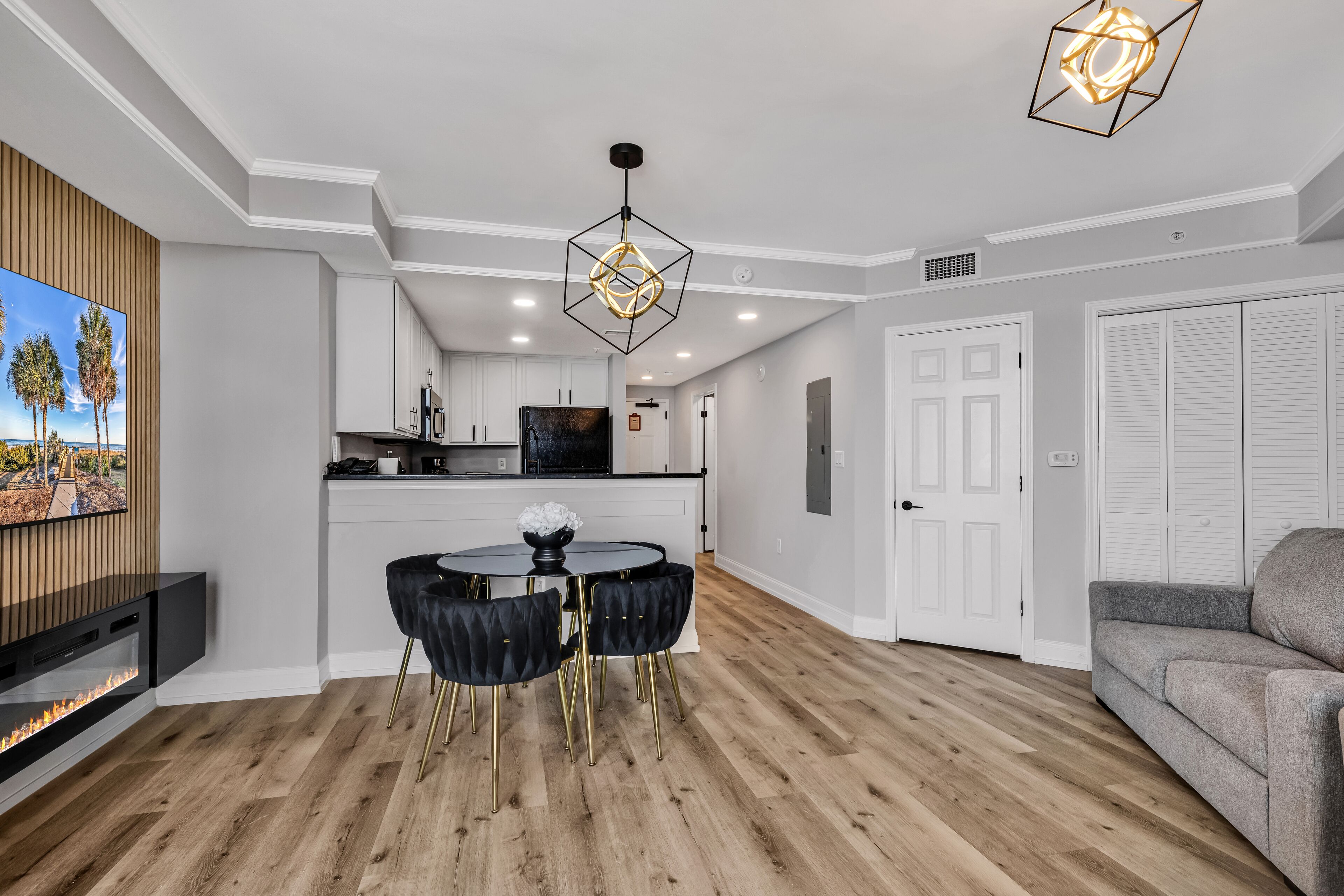 A modern kitchen with white cabinets, a black countertop, and a dining area with a round table and black chairs.