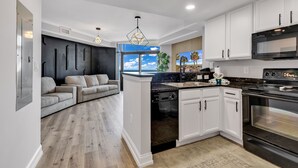 A modern kitchen with white cabinets, a black stove, and a built-in dishwasher. - Beachfront Anderson Condos by Hosteeva (Myrtle Beach)