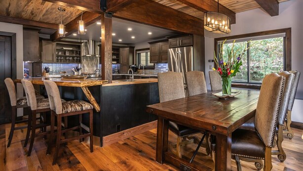 A spacious kitchen with dark wood cabinetry, a central island with seating, and a dining area with a wooden table and chairs.