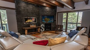 A modern living room with a stone wall, a fireplace, a large sofa, and a television.