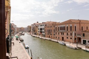 A canal with boats docked along the side, buildings with arched windows, and a clear sky. - Cà Bellavista - View on the canal (Venezia)