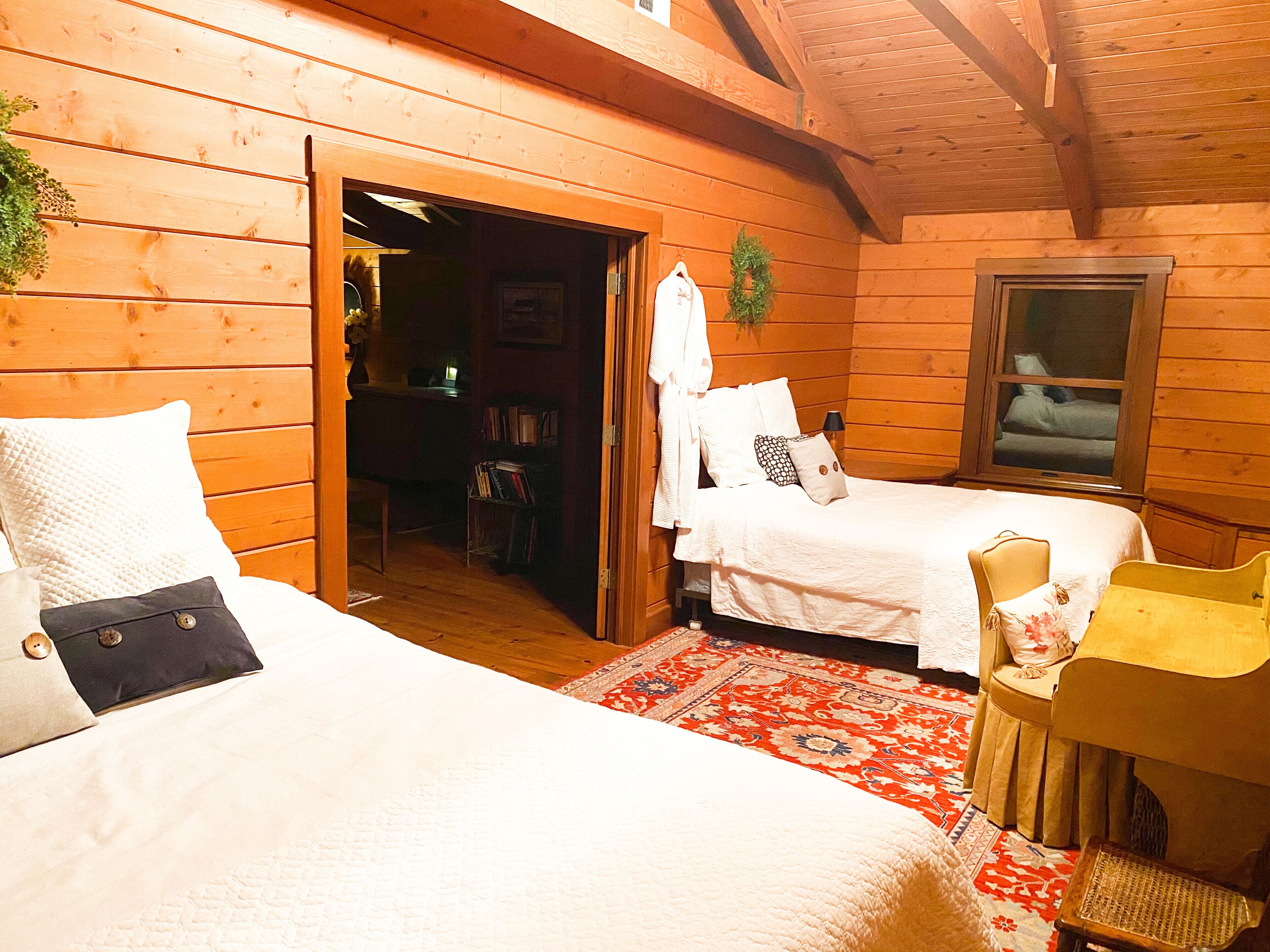 Une chambre confortable, aménagée dans un chalet en bois, avec deux lits, une petite chaise et une fenêtre.