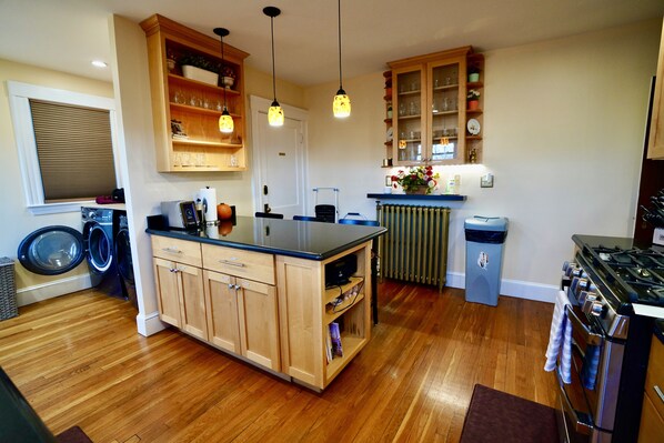 A kitchen with wooden cabinets, a central island, a stove, and a washing machine.
