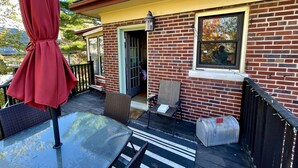 A brick house with a covered patio, a table, chairs, and a red umbrella. - "The In & Out Room" at TPH - Boston (Boston)