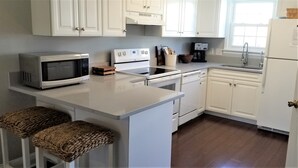 A kitchen with white cabinets, a microwave, an oven, a coffee maker, and a sink. - Island House D : Stylish Updated Townhome - Steps to the Beach w/ Pool! (Surfside Beach)