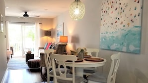 A dining area with a round table, white chairs, and a patterned rug. - Island House D : Stylish Updated Townhome - Steps to the Beach w/ Pool! (Surfside Beach)