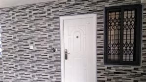 Eine weiße Tür mit modernem Design, eine Wand mit strukturierter Oberfläche und geometrischem Muster sowie ein Fenster mit dekorativem Gitter.