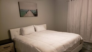 Une chambre à coucher avec un lit, une table de chevet, une commode et un tableau accroché au mur.