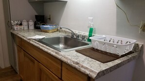 Una cocina con encimera de granito, pileta doble, armarios de madera, cafetera y un cesto de utensilios.