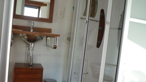 A bathroom with a wooden vanity, a sink, a mirror, and a glass shower enclosure. - Ground floor apartment 3*** classification (Vaulnaveys-le-Haut)