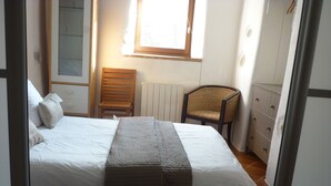 A bedroom with a bed, a chair, a radiator, and a window. - Ground floor apartment 3*** classification (Vaulnaveys-le-Haut)