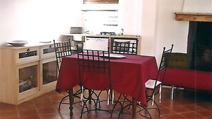 A dining area with a red table and chairs, a kitchen in the background, and a fireplace. - Ground floor apartment 3*** classification (Vaulnaveys-le-Haut)