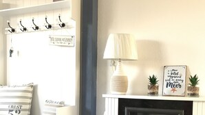 Een knus vertrek met een witte open haard, een lamp en een bord met Duitse tekst.