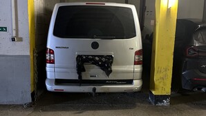 Una camioneta blanca estacionada dentro de un garaje con un pilar amarillo.