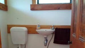 A small bathroom with a toilet, sink, and window. - The Garden Flat: a country apartment close to the beach and daywalks. (Collingwood)
