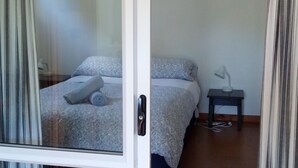 A bedroom with a bed, a nightstand, and a window with curtains. - The Garden Flat: a country apartment close to the beach and daywalks. (Collingwood)