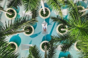 An aerial view of a pool area with palm trees and circular water features.