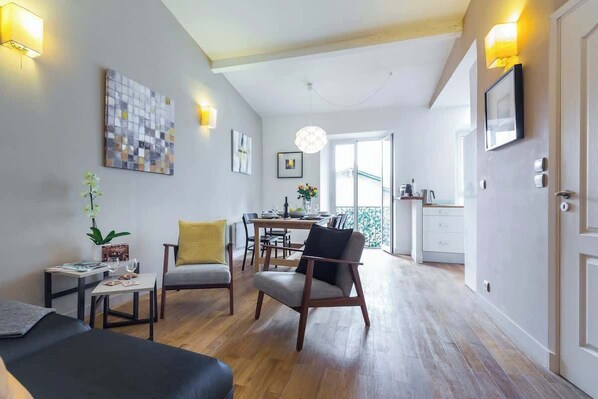Une chambre d’hôtel moderne dotée d’un coin repas, d’un plancher en bois et d’un balcon avec vue.