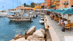 Un port de plaisance avec des bateaux amarrés, une rangée de sièges en plein air et des bâtiments en arrière-plan.