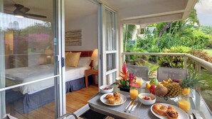 Un balcón con desayuno, una cama y vista a la vegetación.