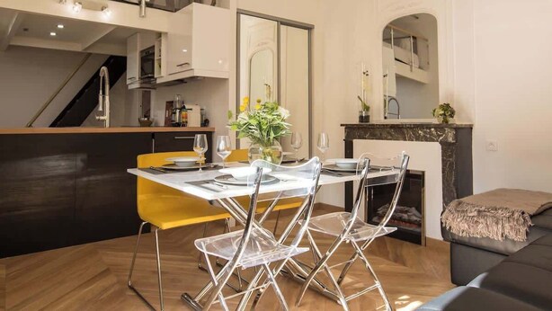 Una cocina moderna con comedor, que cuenta con un techo alto, una escalera y una chimenea.