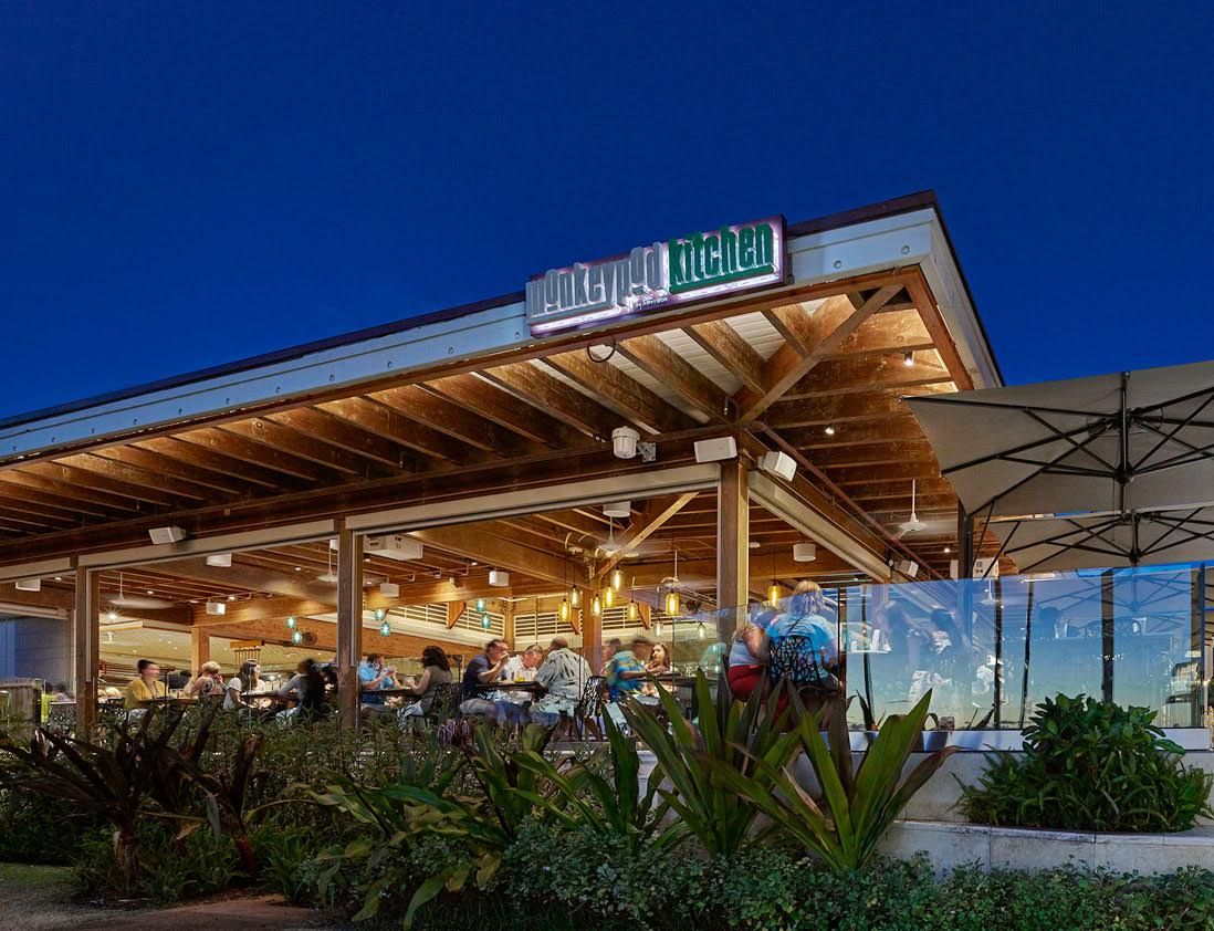 Un espace extérieur aménagé pour les repas, doté d’un coin salon couvert et d’une enseigne indiquant la présence d’un restaurant.