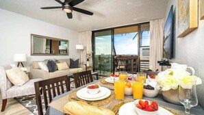 Un coin repas avec une table mise pour le petit-déjeuner, comprenant du pain, des fruits et du jus d’orange.