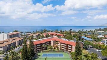 Een resort met meerdere gebouwen, een tennisbaan en uitzicht op de oceaan.