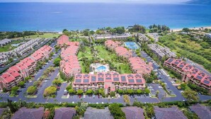 A hotel with a central courtyard, multiple buildings with red roofs, and a view of the ocean. - Luxury Maui Condo | Ocean Views + Resort Perks (Wailea-Makena)