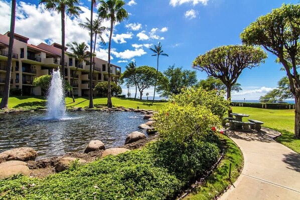 A hotel with a swimming pool, palm trees, and a fountain.