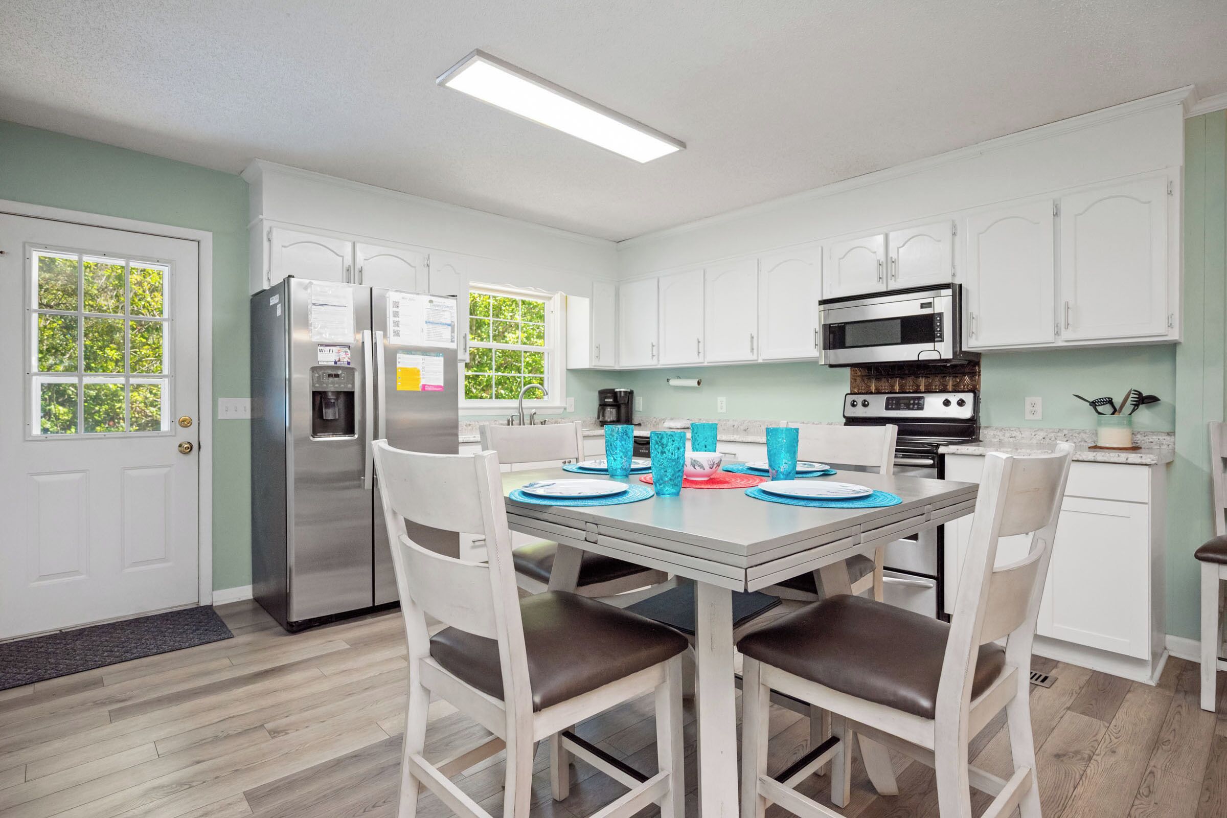 A modern kitchen with white cabinets, stainless steel appliances, and a dining table set for four.