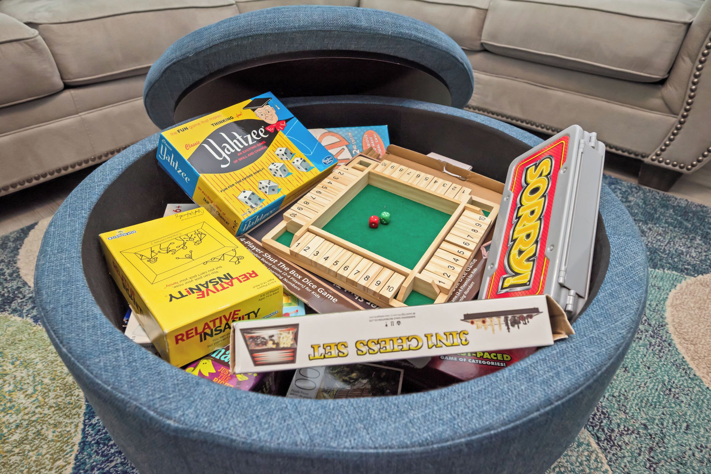 A round coffee table with various board games and a box of dice.