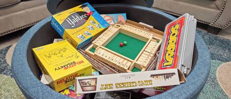 A round coffee table with various board games and a box of dice.