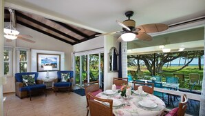 A dining area with a table set for four, surrounded by wicker chairs and a view of the outdoors.