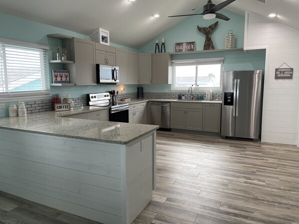 A modern kitchen with a central island, stainless steel appliances, and a view to the outdoors. - *STEPS from BEACH in LaPlaya with private neighborhood boardwalk!!! (Port Aransas)