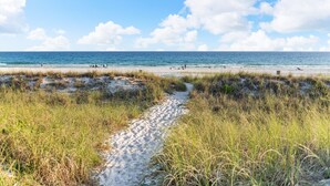 Een strandpad dat naar de oceaan leidt, met mensen in de verte.