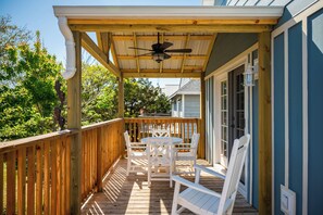 A wooden deck with a ceiling fan, white chairs, and a table. - Pelican Park: Dog-friendly Home Overlooking Canal with Backyard Fireplace, Just (Oak Island)