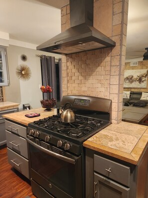 Una cocina con estufa a gas, horno y una campana extractora moderna.