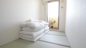 Quarto com uma cama, uma janela e um vaso de planta.