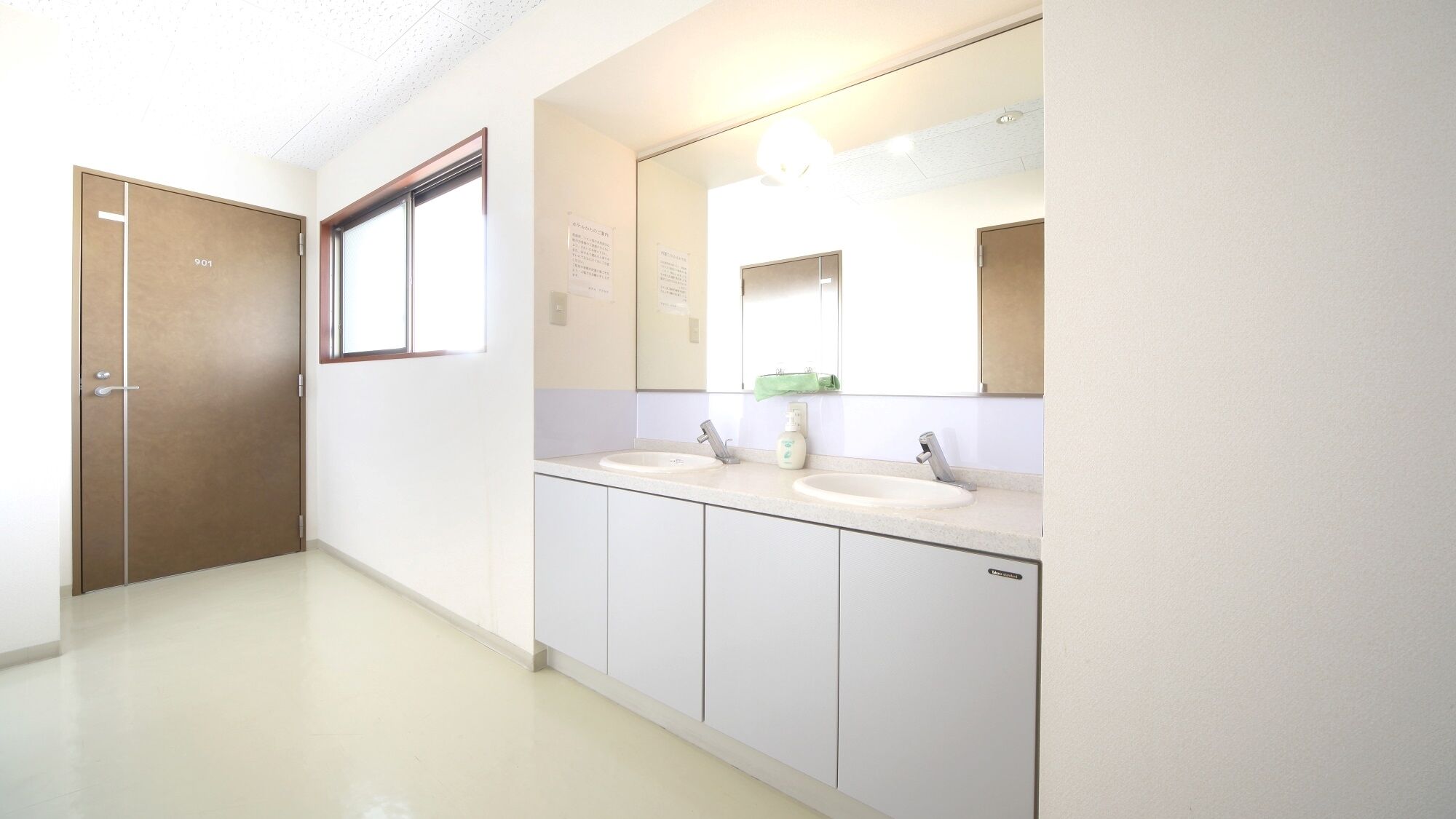 Een badkamer met twee wasbakken, een spiegel en een deur.