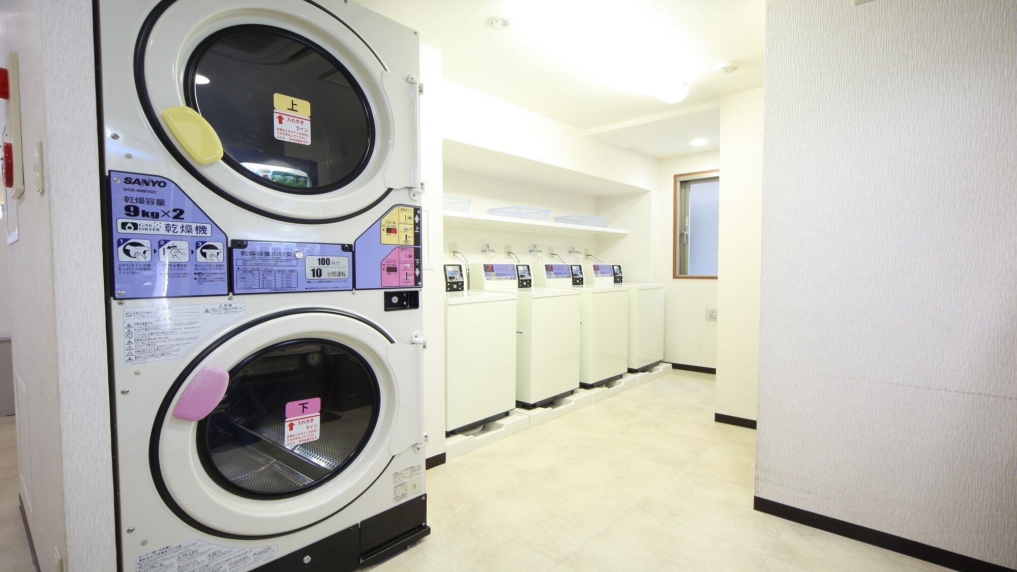 A laundry facility with multiple washing machines, a control panel, and a sign indicating a 10-minute cycle time.